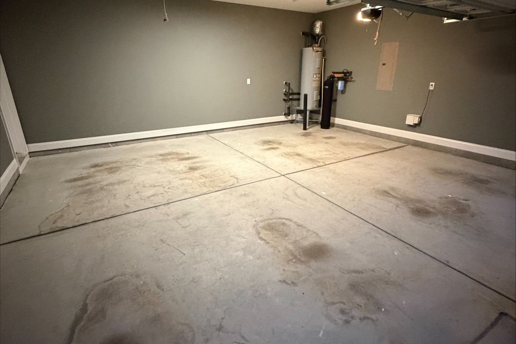 residential garage with stained concrete floor and visible oil marks prior to epoxy floor coating