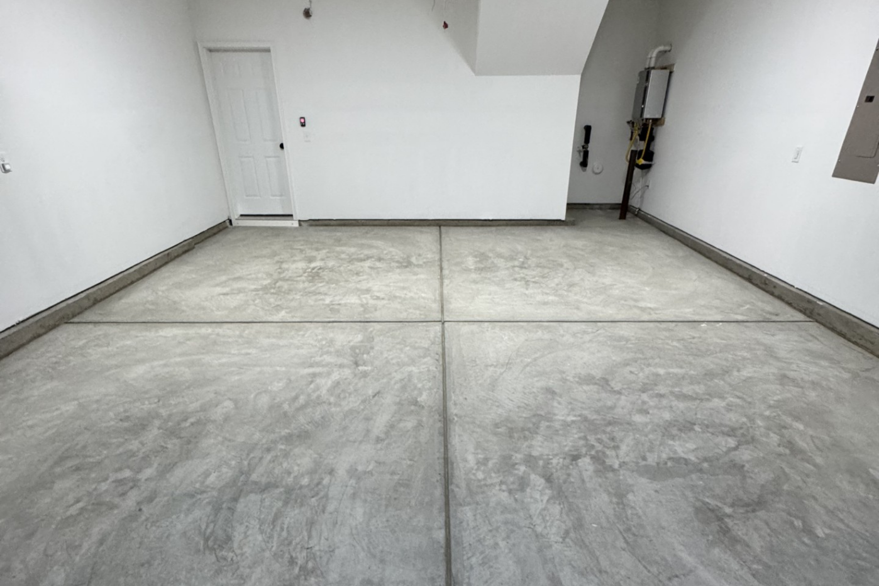 residential garage with unfinished concrete floor showing control joints and surface wear before epoxy coating
