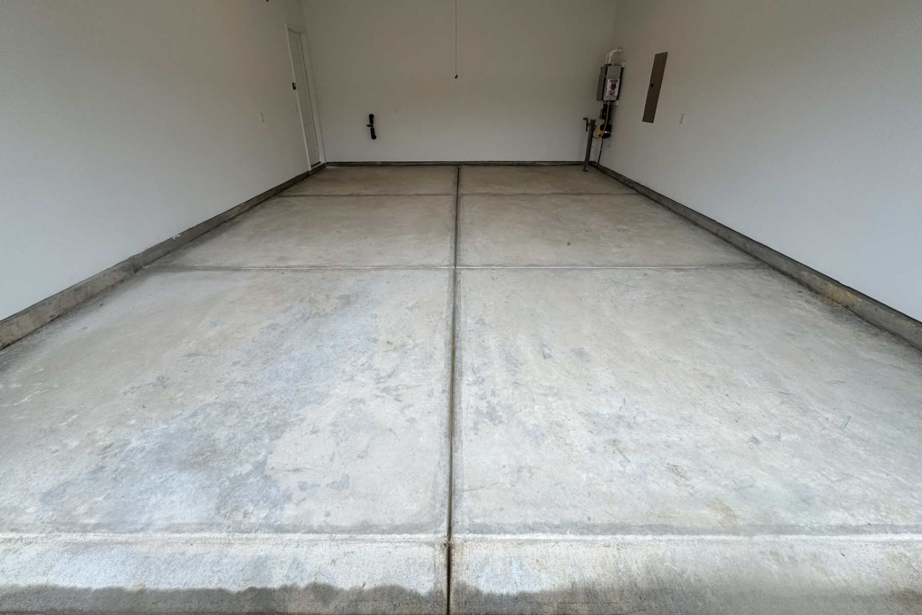 residential garage with unfinished concrete floor showing control joints and surface wear before epoxy coating
