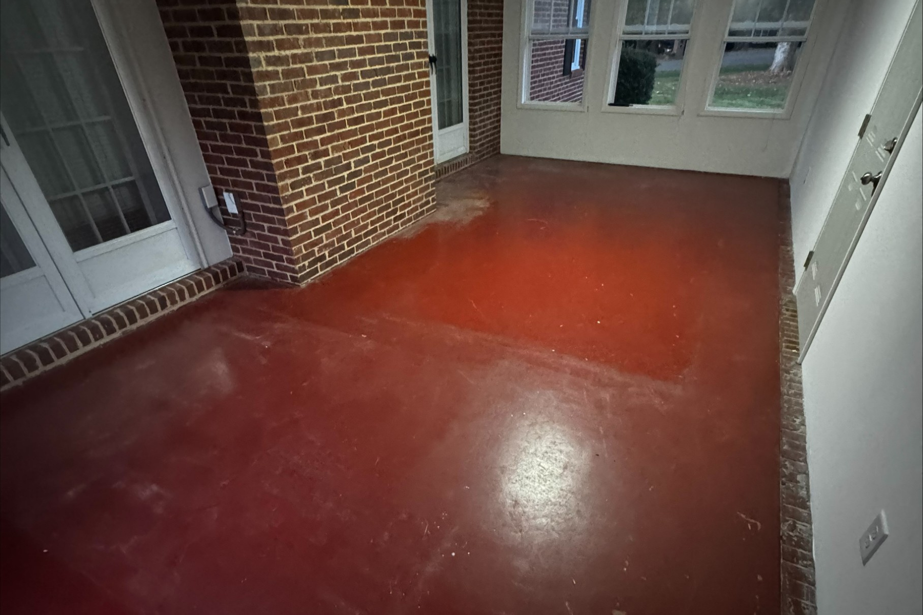 covered brick porch with aged red concrete floor showing wear and surface discoloration before coating